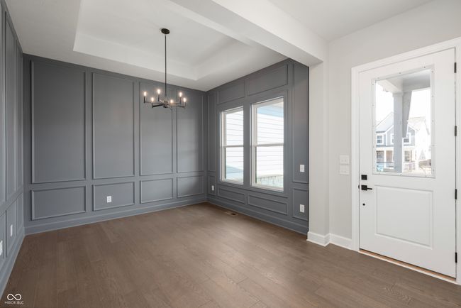 Foyer with a raised ceiling, dark wood-type flooring, a chandelier, and a decorative wall. | Image 4