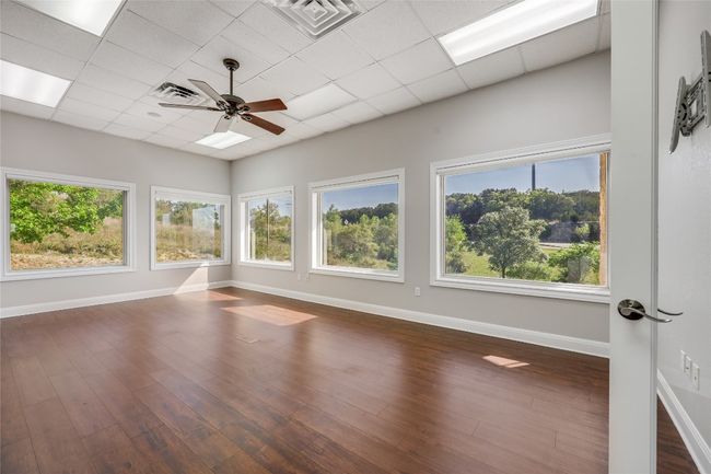 Unfurnished room featuring dark wood finished floors, baseboards, a ceiling fan, and visible vents | Image 11