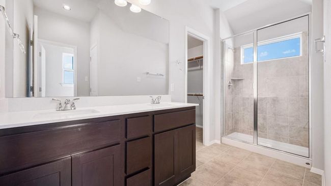 Bathroom featuring a stall shower, double vanity, a walk in closet, and tile patterned flooring | Image 17