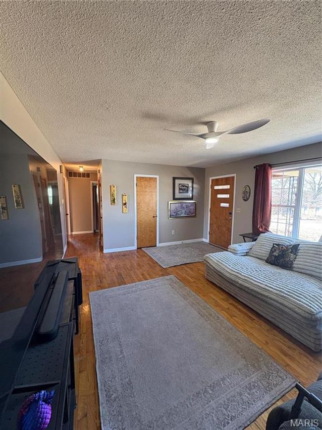 Unfurnished bedroom with baseboards, a textured ceiling, a ceiling fan, and wood finished floors | Image 10