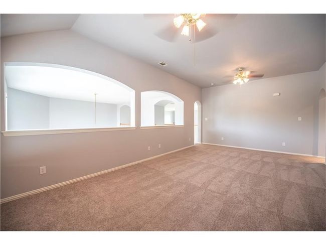 Spare room featuring a ceiling fan, carpet floors, baseboards, and vaulted ceiling | Image 9