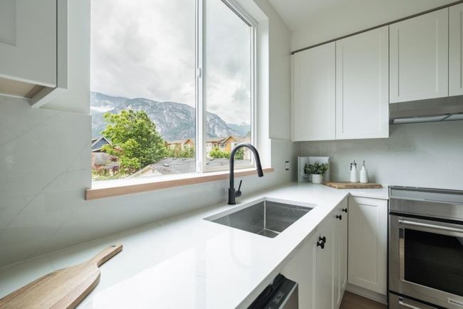 Kitchen with electric stove, a mountain view, under cabinet range hood, white cabinets, and light countertops | Image 9