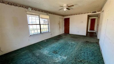 Carpeted empty room featuring ceiling fan and a textured ceiling | Image 3