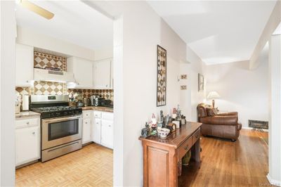 Kitchen featuring white cabinetry, ceiling fan, decorative backsplash, and gas stove | Image 3