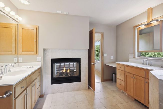 Cozy, double sided fireplace shared with luxurious, primary bedroom. Dual vanities offers fantastic, separated space and abundance of storage for all the accessories. | Image 26