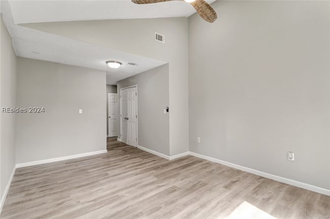 Spare room with high vaulted ceiling, light wood-type flooring, and ceiling fan | Image 12