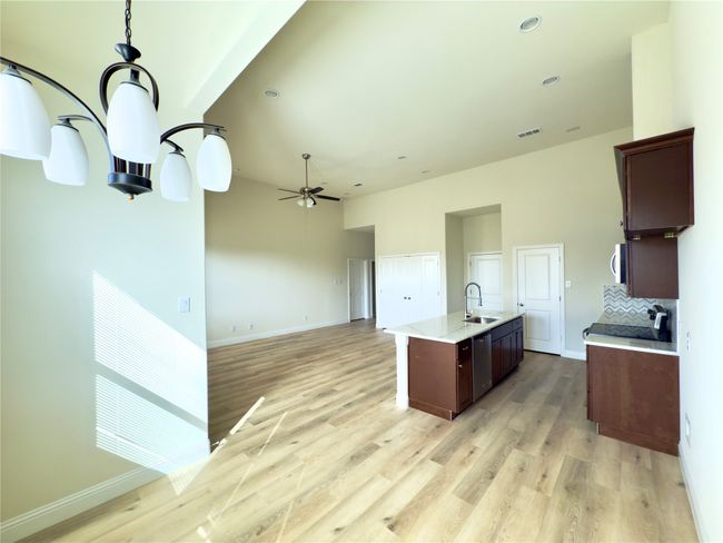 Kitchen featuring stainless steel dishwasher, a sink, ceiling fan, light wood finished floors, and a kitchen island with sink | Image 22