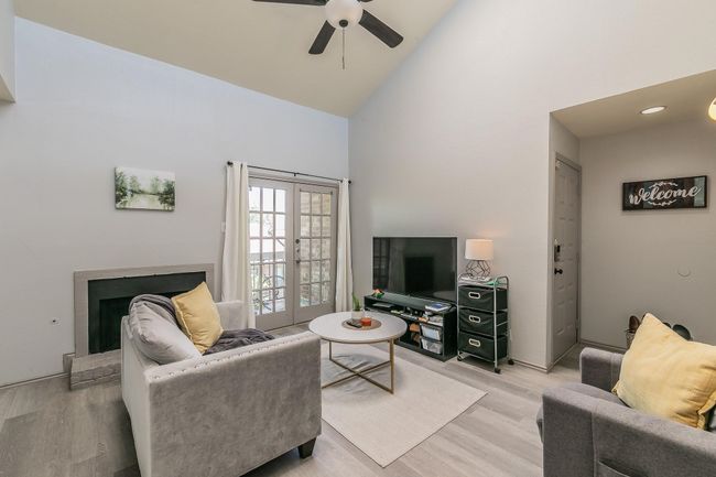 Living room with high vaulted ceiling, ceiling fan, french doors, and light wood-type flooring | Image 19