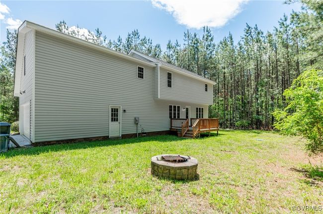 Back of property featuring a fire pit, a lawn, and a wooden deck | Image 27