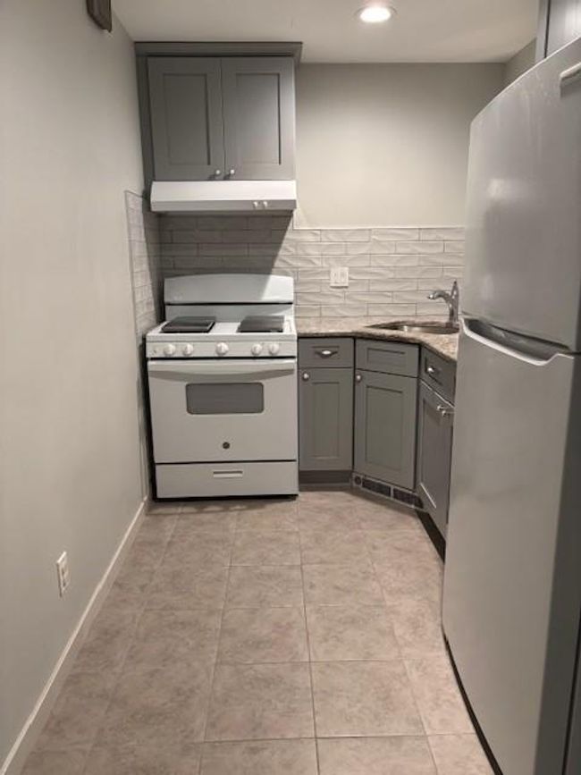 Kitchen featuring refrigerator, range, extractor fan, a sink, and gray cabinetry | Image 6
