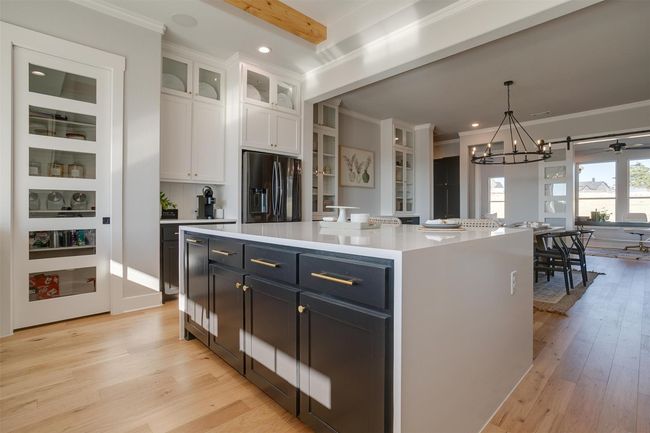 Kitchen with stainless steel refrigerator with ice dispenser, beamed ceiling, white cabinets, a kitchen island, and hanging light fixtures | Image 13
