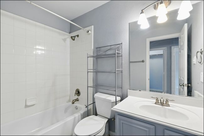 Bathroom featuring vanity, a textured wall, toilet, and shower / washtub combination | Image 24