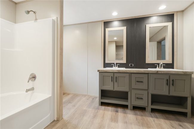 Full bath featuring wood finished floors, shower / bathtub combination, double vanity, and a sink | Image 25