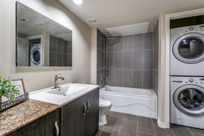 Full bathroom with stacked washer and clothes dryer, vanity, and washtub / shower combination | Image 12