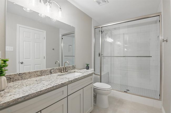 Full bathroom featuring tile patterned floors, toilet, a stall shower, visible vents, and vanity | Image 17