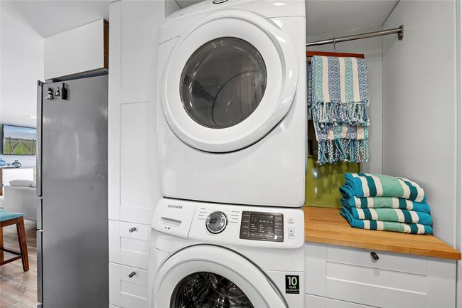 Washroom featuring laundry area, wood finished floors, and stacked washer and clothes dryer | Image 12