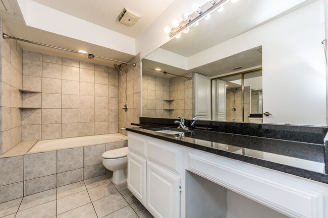 Bathroom with toilet, visible vents, tile patterned flooring, tiled shower / bath combo, and vanity | Image 6