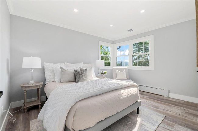 Bedroom with baseboard heating, ornamental molding, wood finished floors, and recessed lighting | Image 16