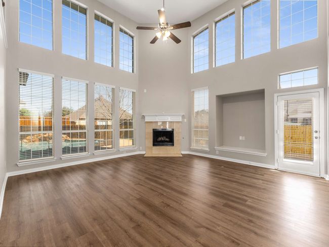 Unfurnished living room featuring a premium fireplace, baseboards, dark wood finished floors, and a ceiling fan | Image 8