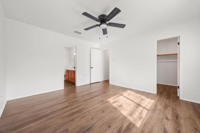 Unfurnished primary bedroom featuring baseboards, visible vents, a spacious closet, and wood finished floors | Image 11