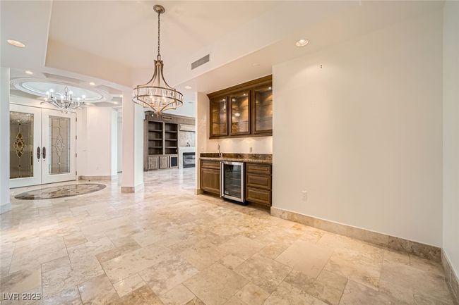 Indoor dry bar featuring beverage cooler, a chandelier, stone tile flooring, baseboards, and recessed lighting | Image 11