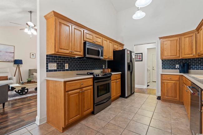 Kitchen featuring appliances with stainless steel finishes, light countertops, light tile patterned floors, a ceiling fan, and a high ceiling | Image 13
