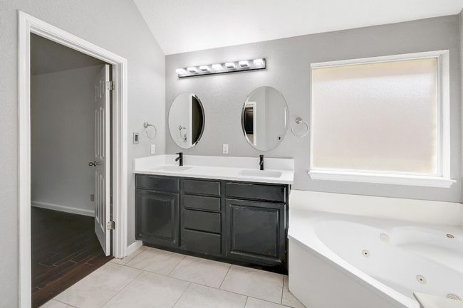Bathroom featuring double vanity, a jetted tub, a sink, and lofted ceiling | Image 23