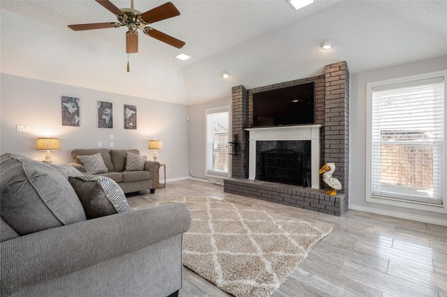 Living area featuring a brick fireplace, vaulted ceiling, and a textured ceiling | Image 7