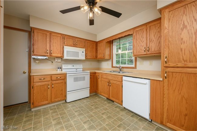 Kitchen featuring white appliances, light countertops, ceiling fan, light flooring, and brown cabinets | Image 11