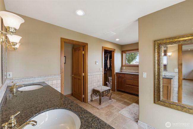 Double vanity and large walk in closet with built in wooden shelves and closet system. | Image 21