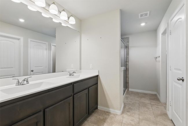 Full bath with double vanity, a stall shower, and baseboards | Image 15