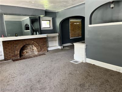 Unfurnished living room with a textured ceiling, carpet floors, and a fireplace | Image 2