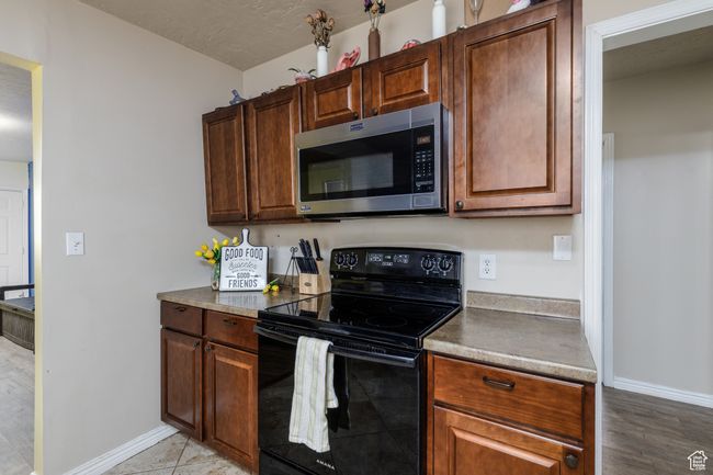 Kitchen featuring stainless steel microwave, black range with electric cooktop, and light wood finished floors | Image 9