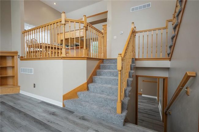 Staircase with wood finished floors, baseboards, a towering ceiling, and recessed lighting | Image 10