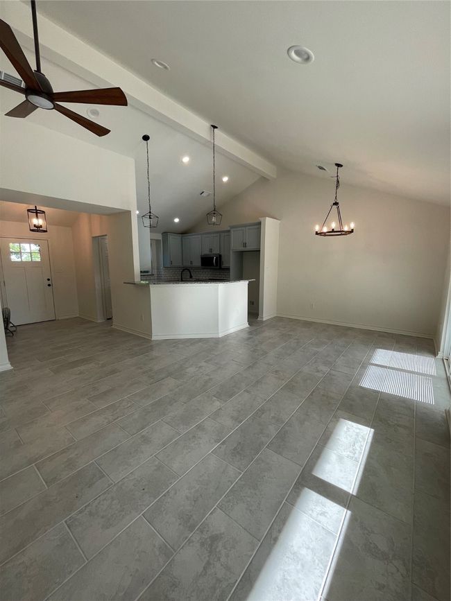 Unfurnished living room with lofted ceiling with beams, a sink, baseboards, recessed lighting, and ceiling fan with notable chandelier | Image 18
