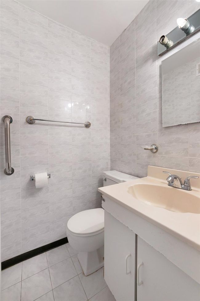 Bathroom with toilet, tile walls, tile patterned flooring, and vanity | Image 11