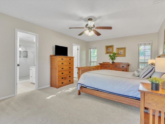Carpeted bedroom featuring baseboards, a ceiling fan, and ensuite bath | Image 22