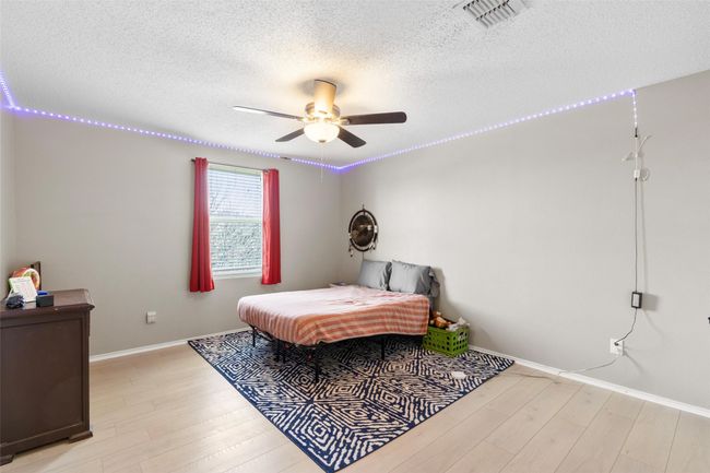 Bedroom with a textured ceiling, light wood-style flooring, and a ceiling fan | Image 26