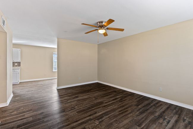 Spare room featuring ceiling fan, dark wood-type flooring, visible vents, and baseboards | Image 9