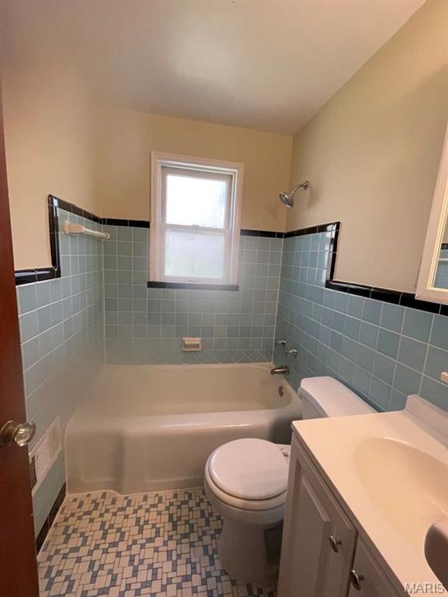 Full bath with tile patterned floors, vanity, tile walls, toilet, and shower / bathtub combination | Image 18