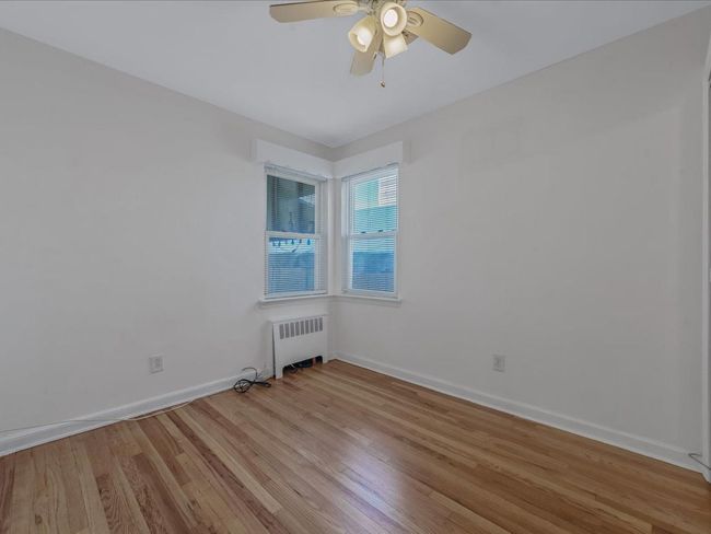 Spare room featuring radiator heating unit, light wood finished floors, and a ceiling fan | Image 14