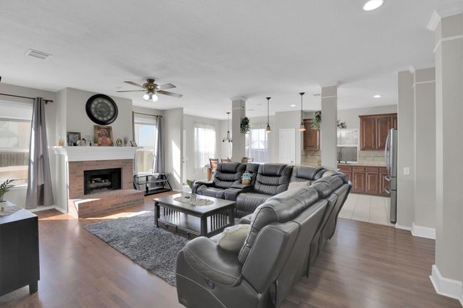 Living room featuring a fireplace, visible vents, baseboards, dark wood finished floors, and decorative columns | Image 8