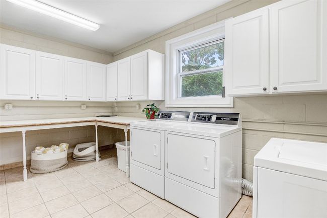 Laundry room with cabinet space, washing machine and clothes dryer, and light tile patterned flooring | Image 29