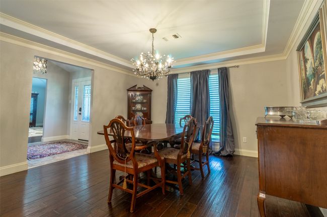 Dining area with a chandelier, ornamental molding, a raised ceiling, dark wood-style floors, and healthy amount of natural light | Image 13