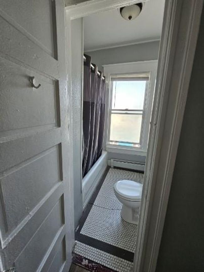 Full bath with toilet, a baseboard heating unit, tile patterned floors, shower / bath combo, and ornamental molding | Image 4