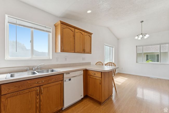 Kitchen with dishwasher, a peninsula, light wood-style flooring, light countertops, and vaulted ceiling | Image 8