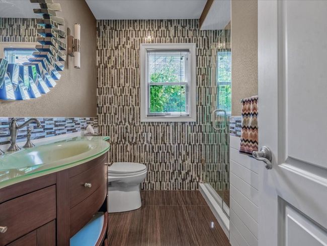 Bathroom featuring tile walls, vanity, toilet, and a shower stall | Image 15