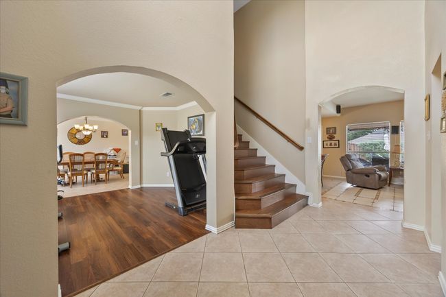 Foyer entrance with arched walkways, light tile patterned floors, stairway, ornamental molding, and a towering ceiling | Image 6