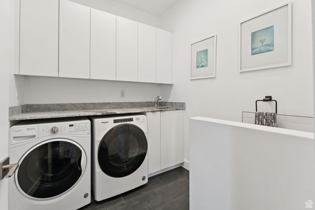 Laundry area featuring separate washer and dryer, cabinet space, and dark tile patterned floors | Image 38