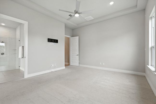 Primary suite bedroom with light colored carpet, recessed lighting, ensuite bath, and a ceiling fan | Image 17